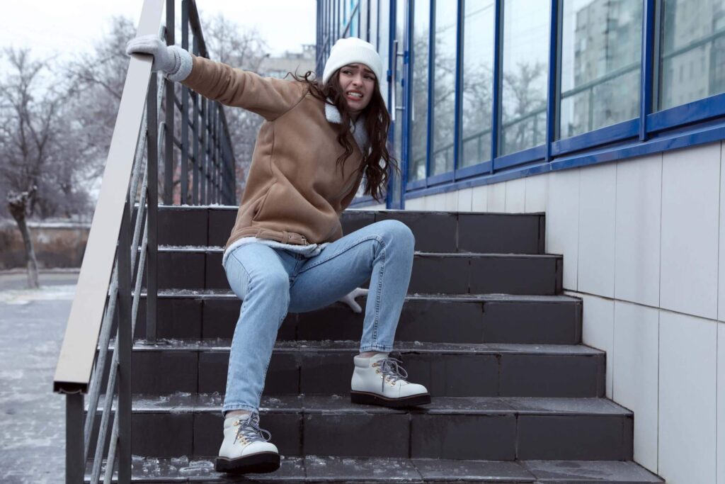 Young woman falls on slippery ice Young woman falls on slippery ice-covered stairs outdoors